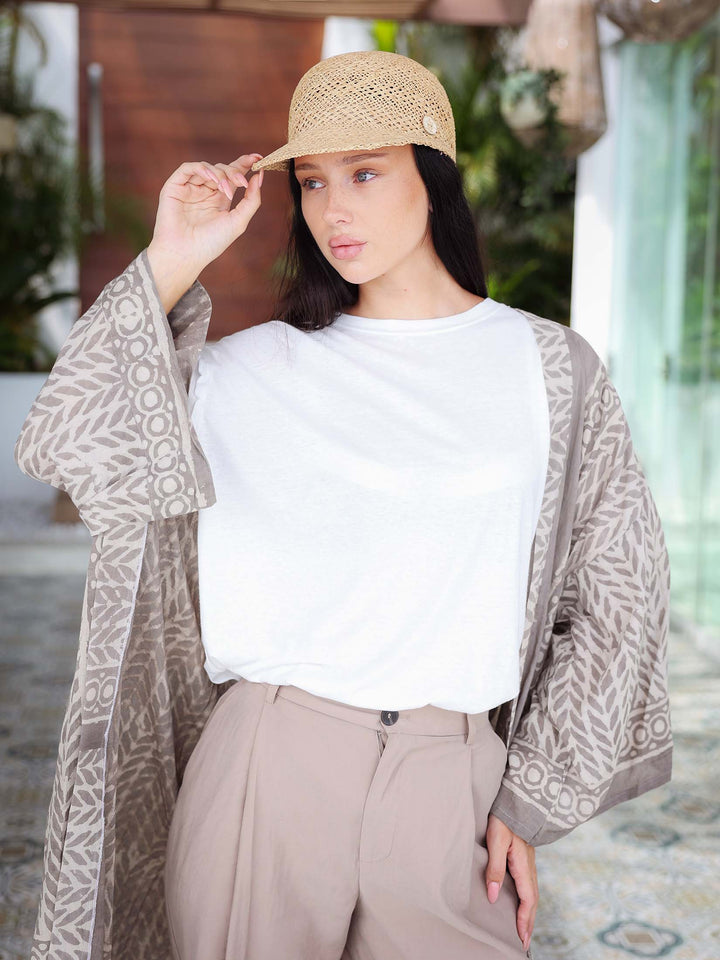Woman wearing a beige hat and patterned kimono in an outdoor setting
